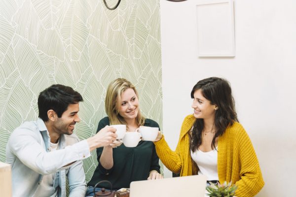 happy-friends-clinking-mugs-with-tea